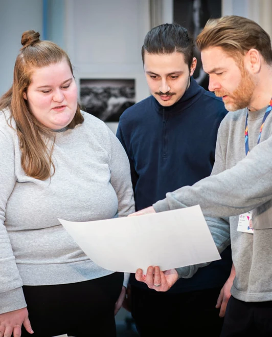 Lecturer showing two students a large print during a group discussion in the studio. Lecturer showing two students a large print during a group discussion in the studio.